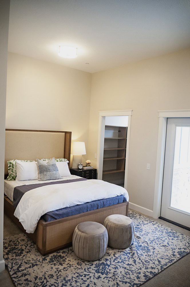 A cozy bedroom featuring a neatly made bed with decorative pillows, a bedside lamp, and an area rug.