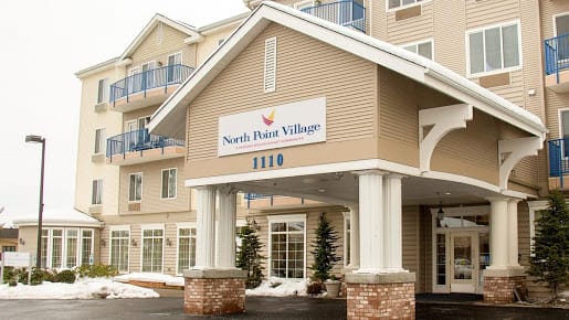 The entrance of North Hill Village with a prominent sign and snowy surroundings.