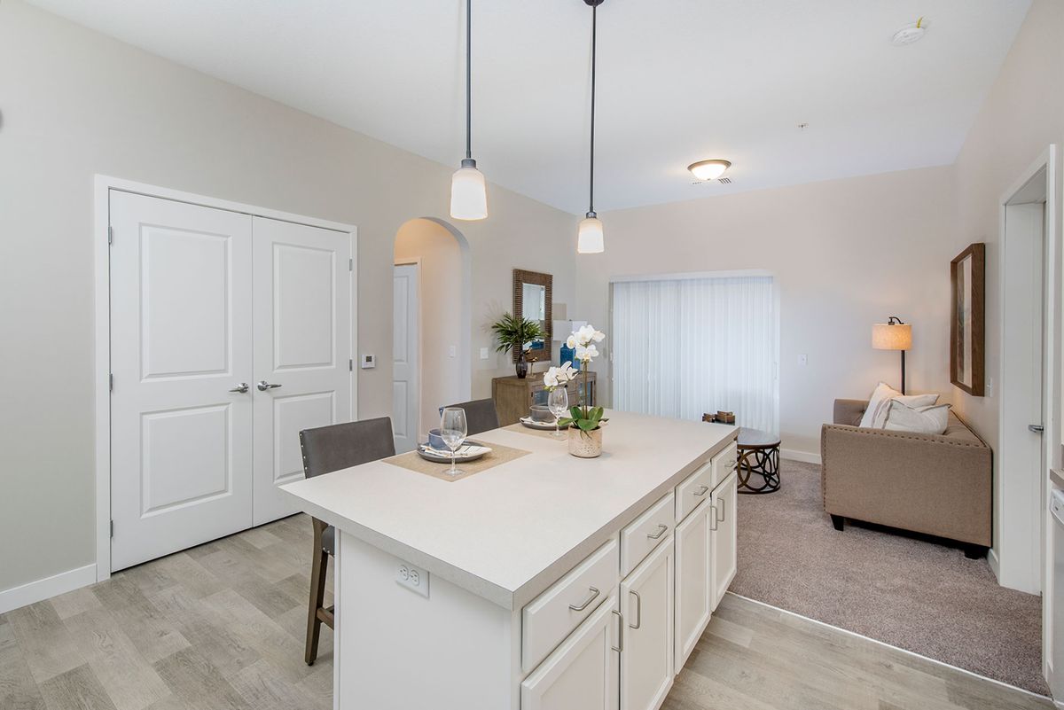 A modern, minimalist kitchen with a central island and pendant lighting.