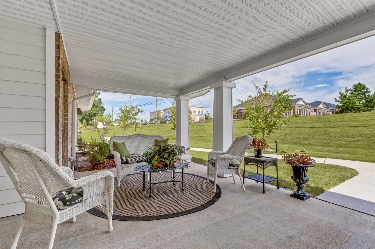 A cozy porch with elegant wicker furniture and a scenic garden view.