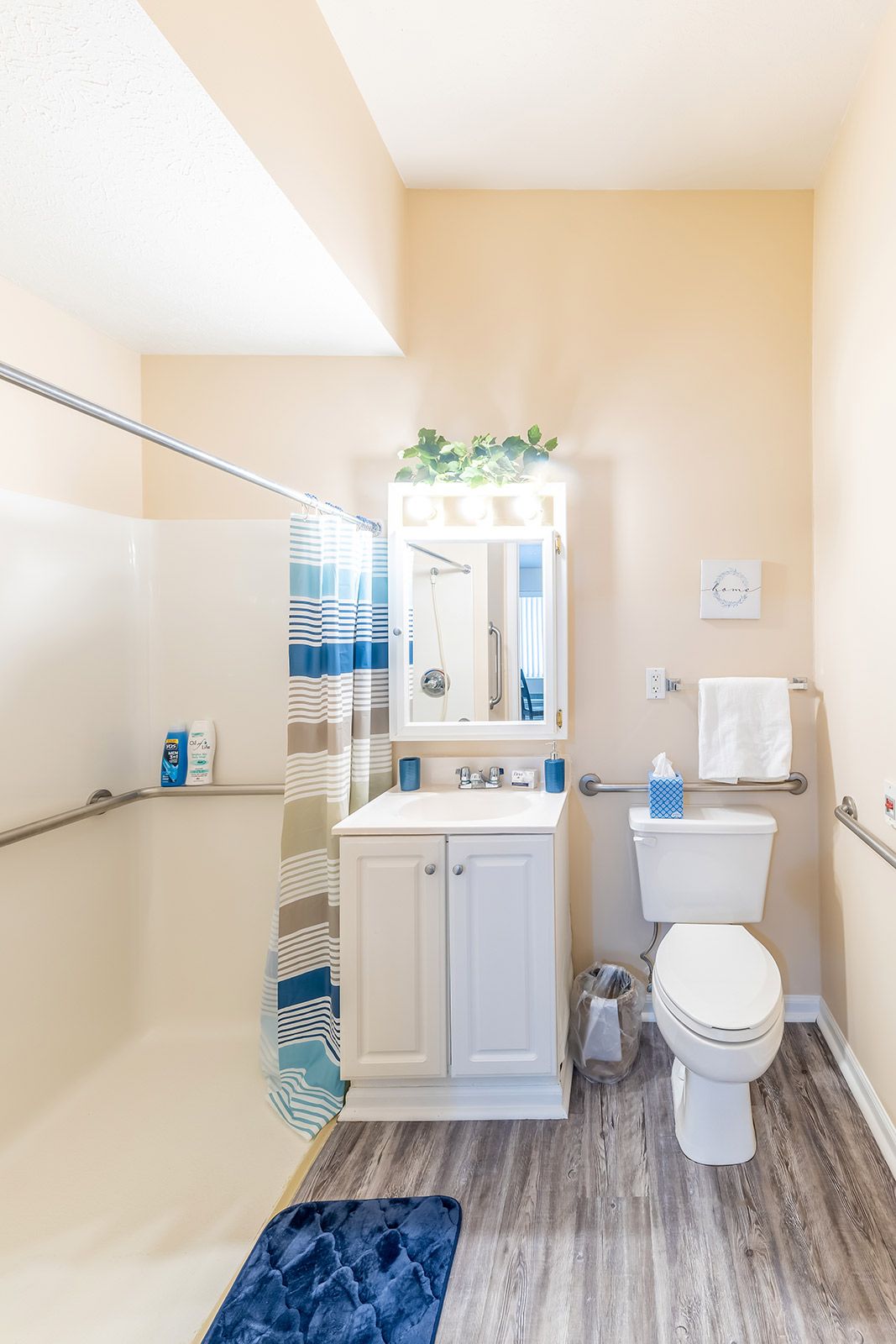 A well-lit bathroom with a shower, sink, and toilet.