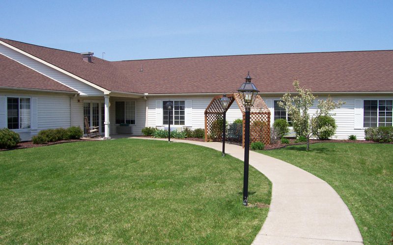 A single-story house with a well-maintained lawn and pathway lined with lamp posts.