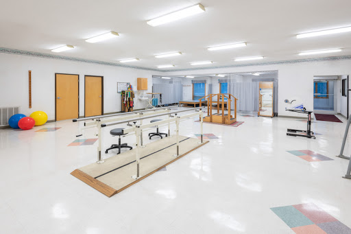 A spacious and well-lit physical therapy rehabilitation center, equipped with various exercise equipment and treatment areas.