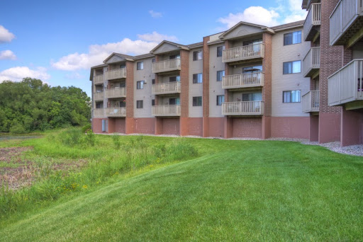 A modern apartment building with balconies set against a lush green landscape.