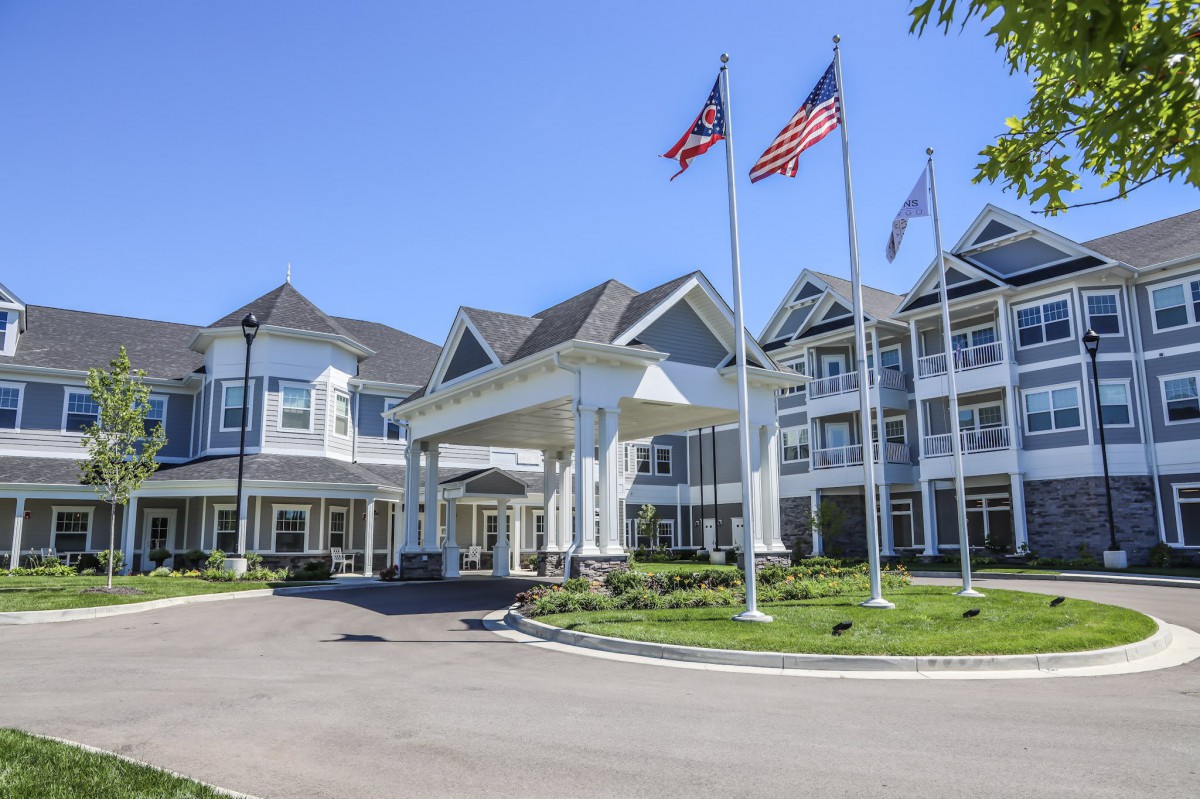 A large residential building with a grand entrance and multiple flags flying on a sunny day.