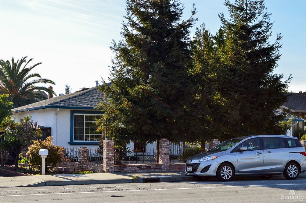 A suburban house with a car parked on the street in front.