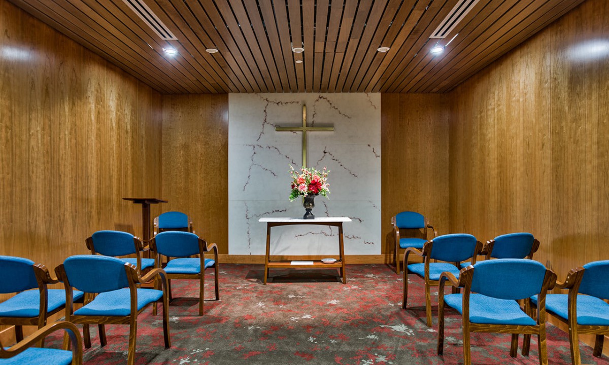 A small chapel with a cross, altar, and seating arranged in a cozy setting.