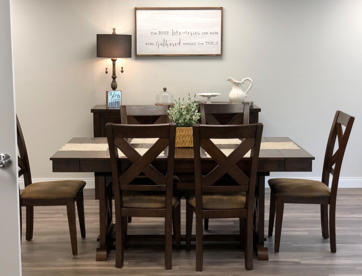A cozy dining room setup with a wooden table and chairs, accented by a lamp and wall decor.