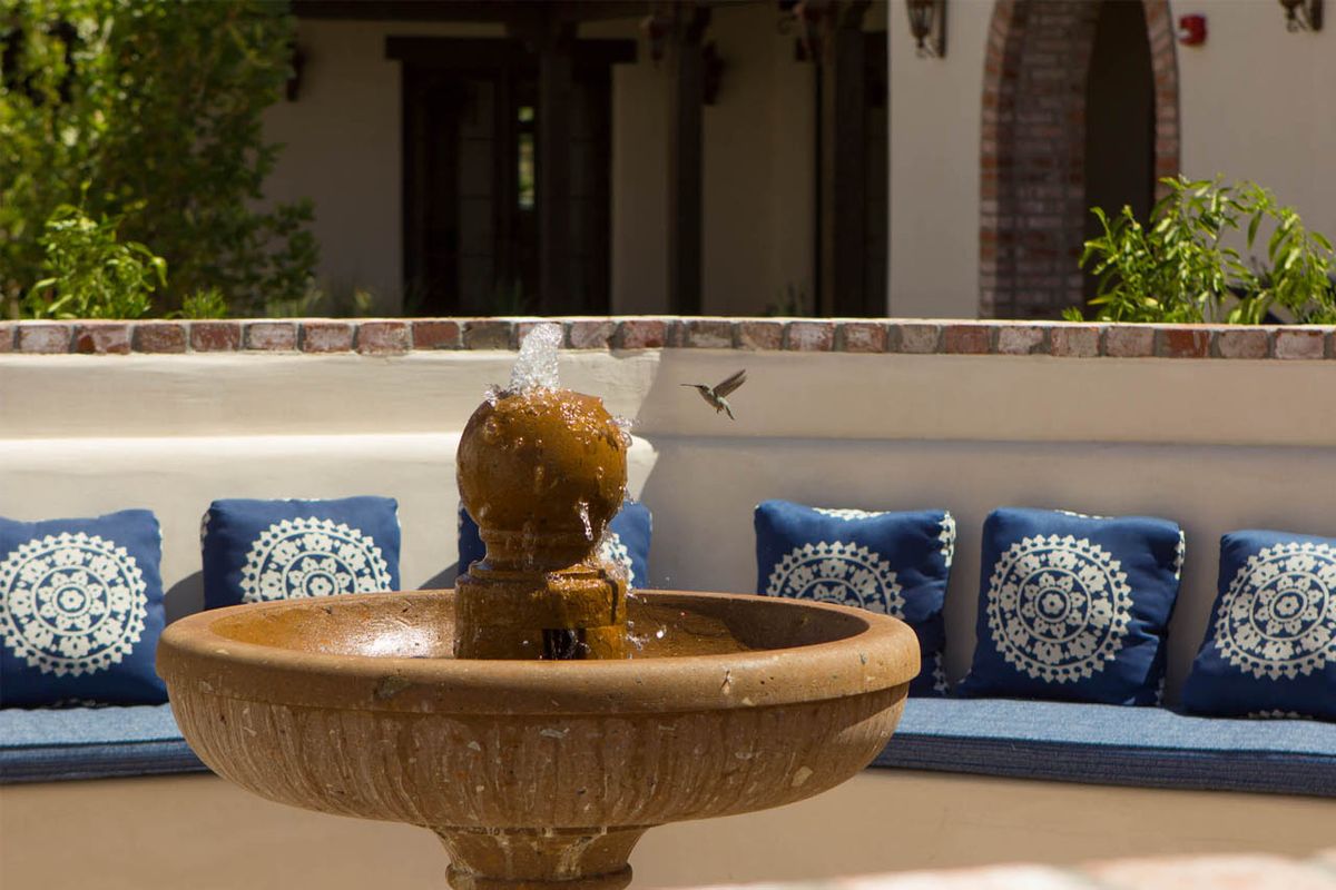 A serene courtyard with a central fountain and comfortable blue cushioned seating.