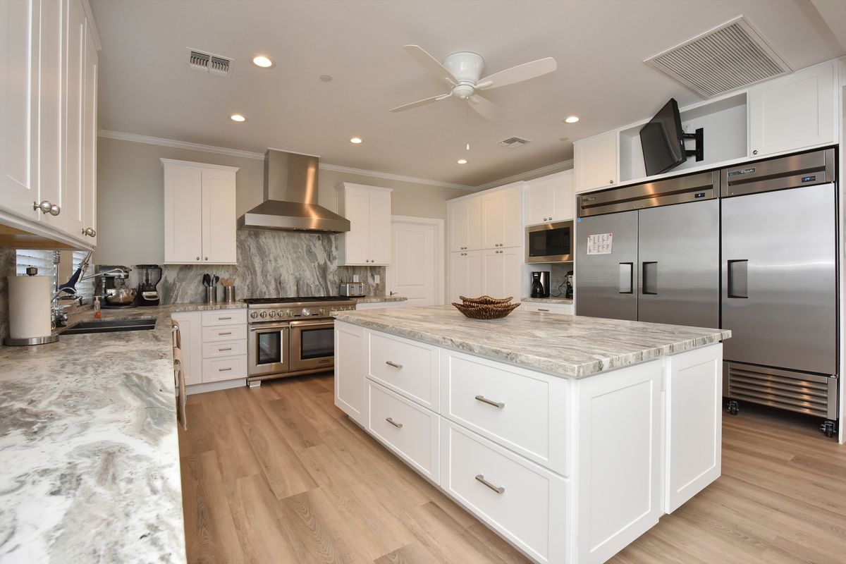 A modern kitchen with a central island, featuring stainless steel appliances and white cabinets.