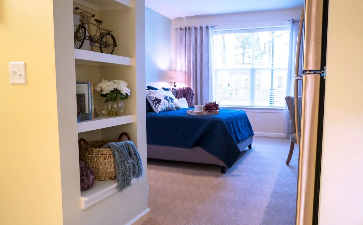 A cozy bedroom with decorative shelves and a large window letting in natural light.