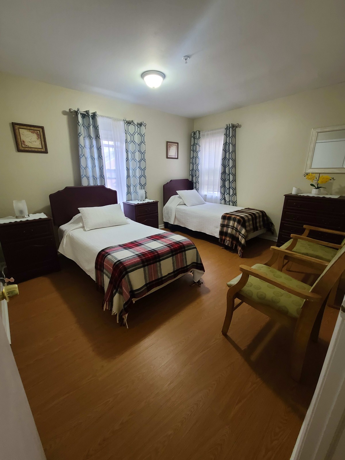A cozy bedroom with twin beds, adorned with checkered blankets and framed artwork.