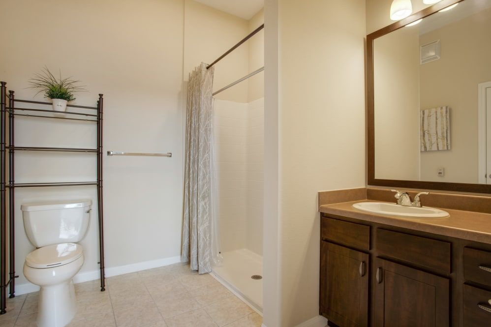 A simple bathroom with a shower, sink, and mirror.