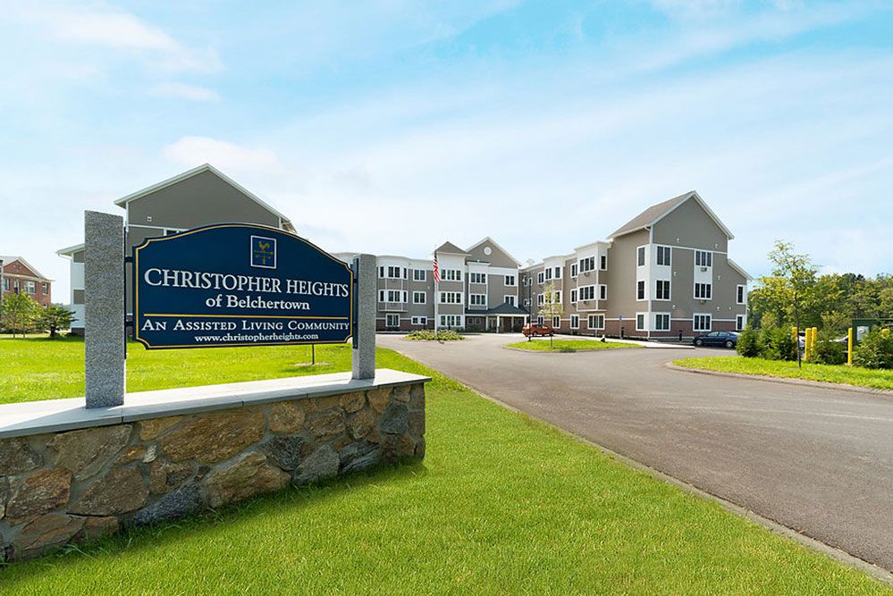 Exterior view of a senior living facility with a sign and landscaped grounds.