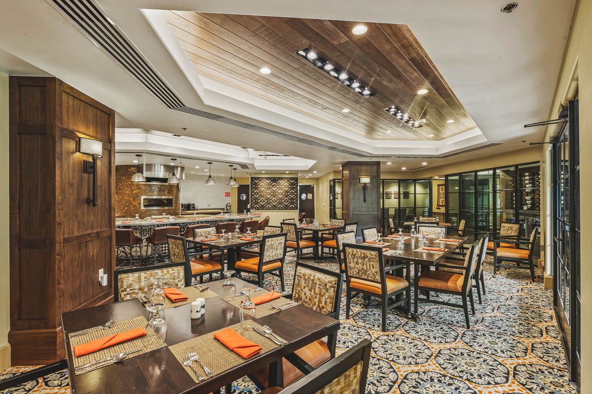 A modern and elegant restaurant dining area with neatly arranged tables and a wooden ceiling.
