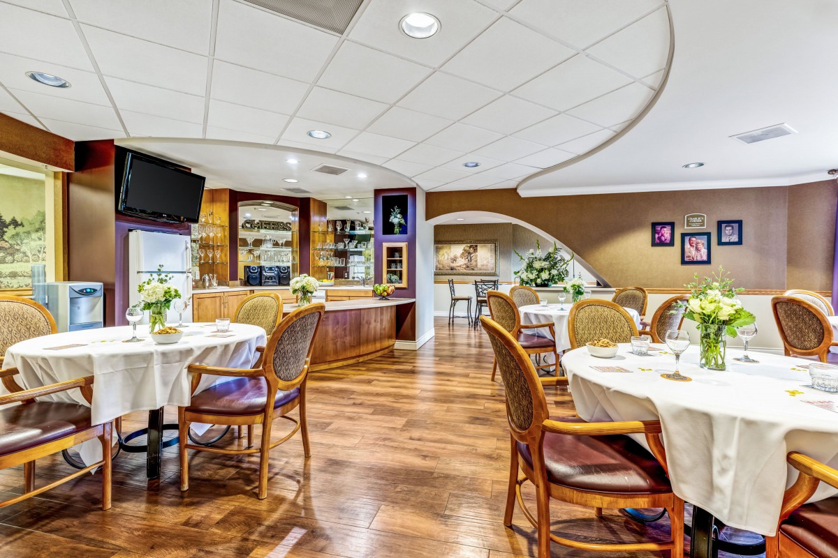 A cozy restaurant dining area with elegantly set tables and comfortable chairs, featuring a wooden floor and tasteful decor.