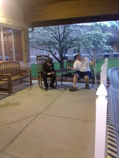 Two individuals seated on a porch enjoying a conversation in the evening.