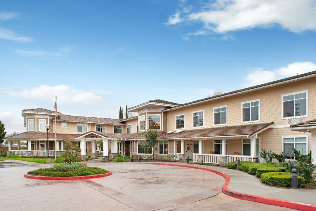 A residential building with a landscaped driveway under a clear blue sky.