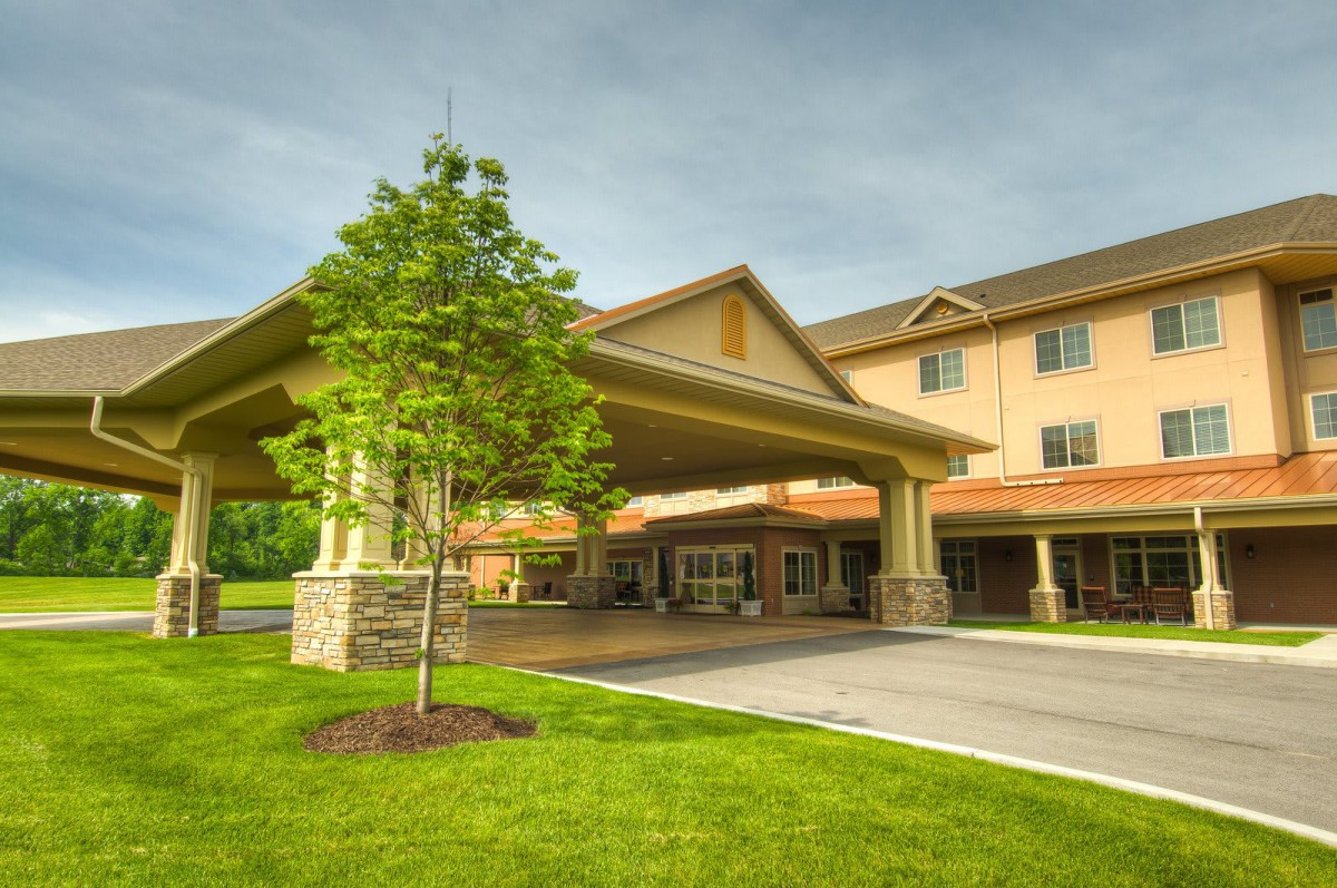 A well-maintained building entrance with a driveway and lush landscaping.