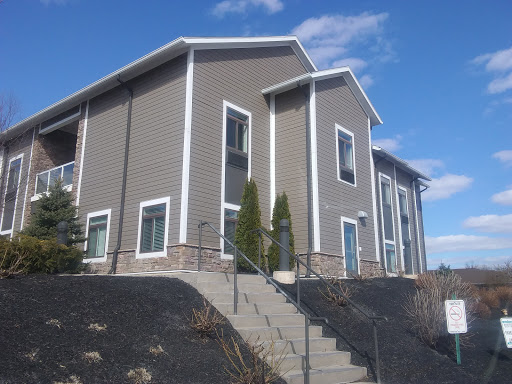 A modern residential building with a landscaped area and stairs leading up to the entrance.