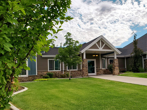 A beautifully designed house set in a lush green landscape with a clear blue sky.