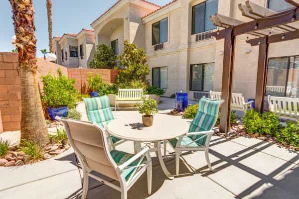 A cozy outdoor patio area with a table and chairs surrounded by plants.
