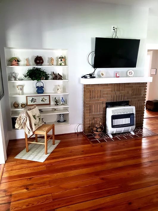 Cozy living room with a fireplace, bookshelves, and wooden flooring.
