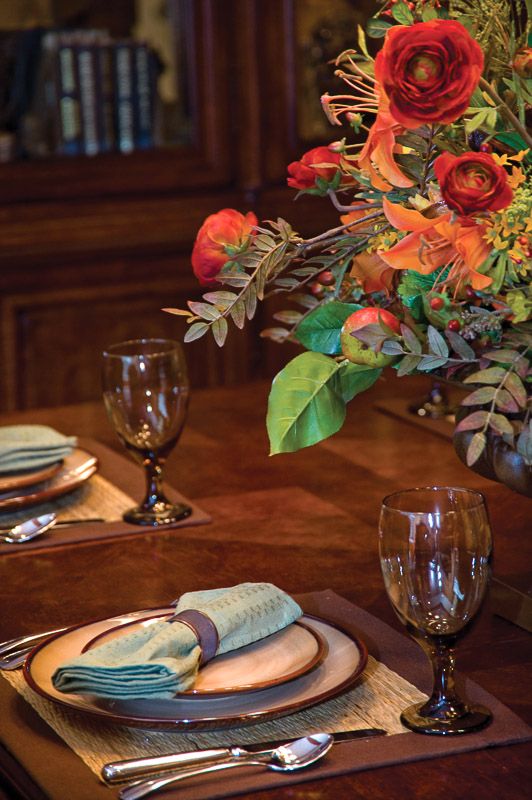 A beautifully set dining table with a vibrant floral arrangement and elegant glassware.