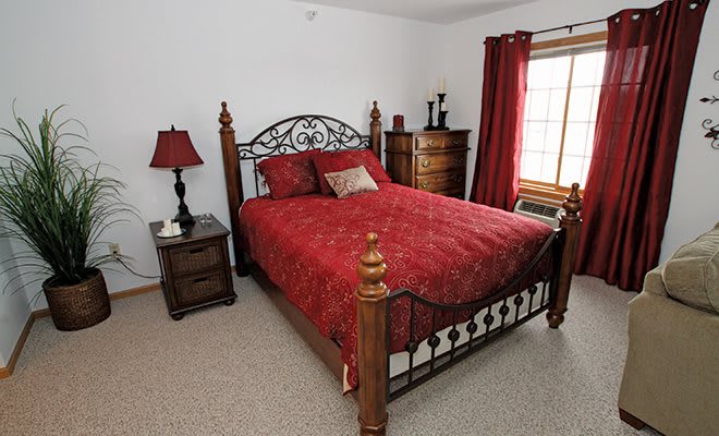 A cozy bedroom with a wooden bed frame and red bedding.