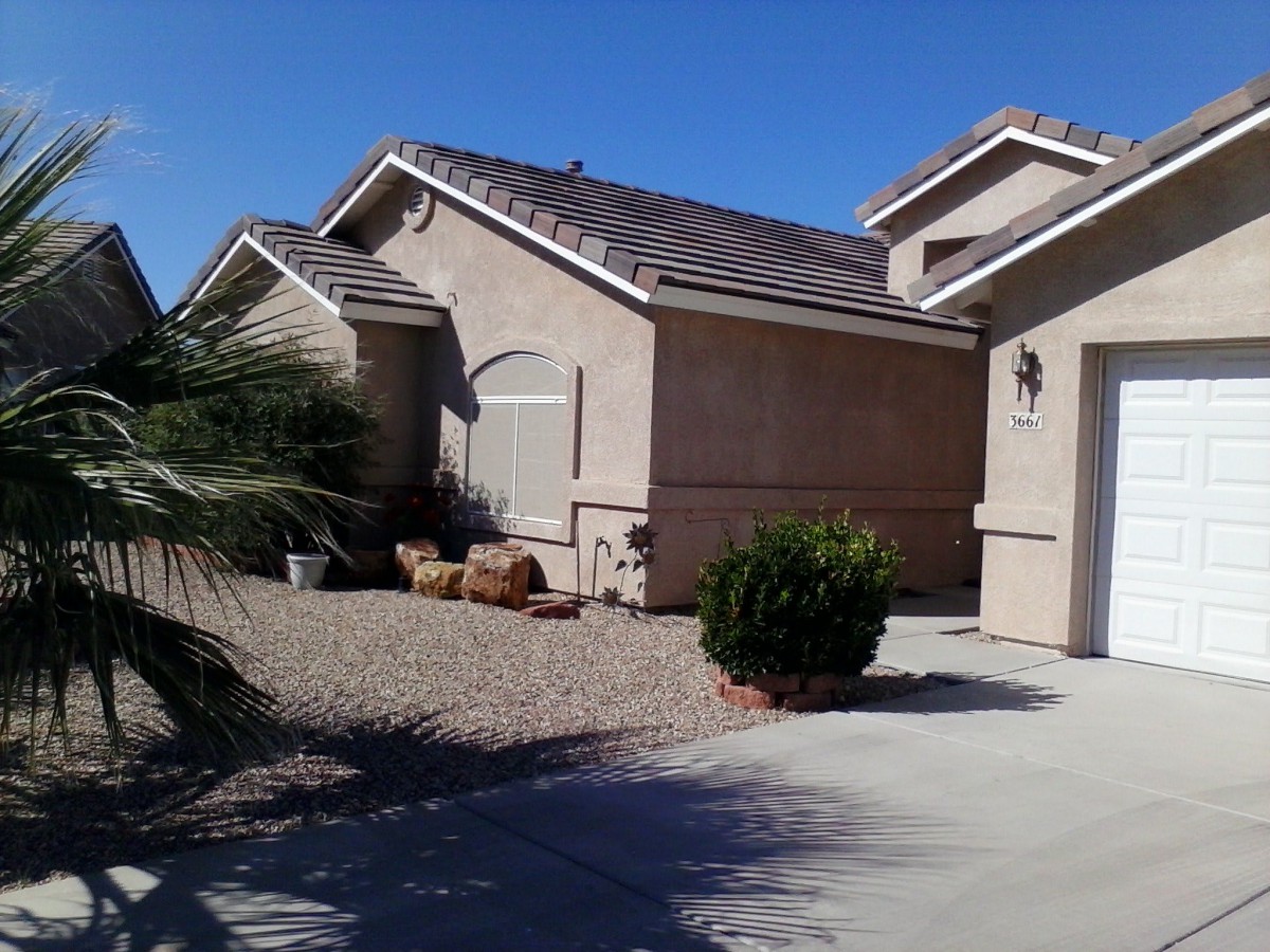 A suburban house with desert landscaping and a driveway under a clear blue sky.