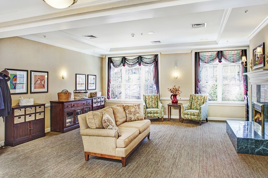 A well-furnished living room with a sofa, chairs, and large windows.