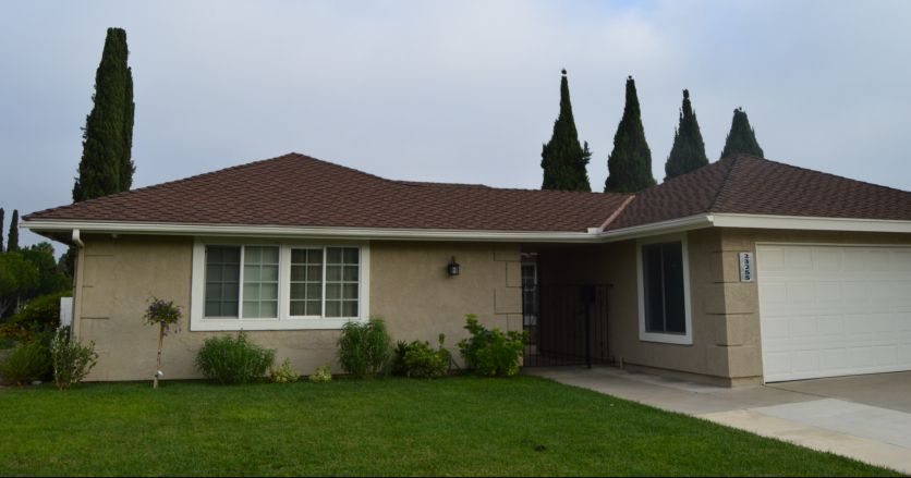 A suburban residential house with a well-maintained lawn and surrounding trees.