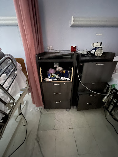 A view of a hospital patient's bedside, featuring two cabinets with medical supplies.