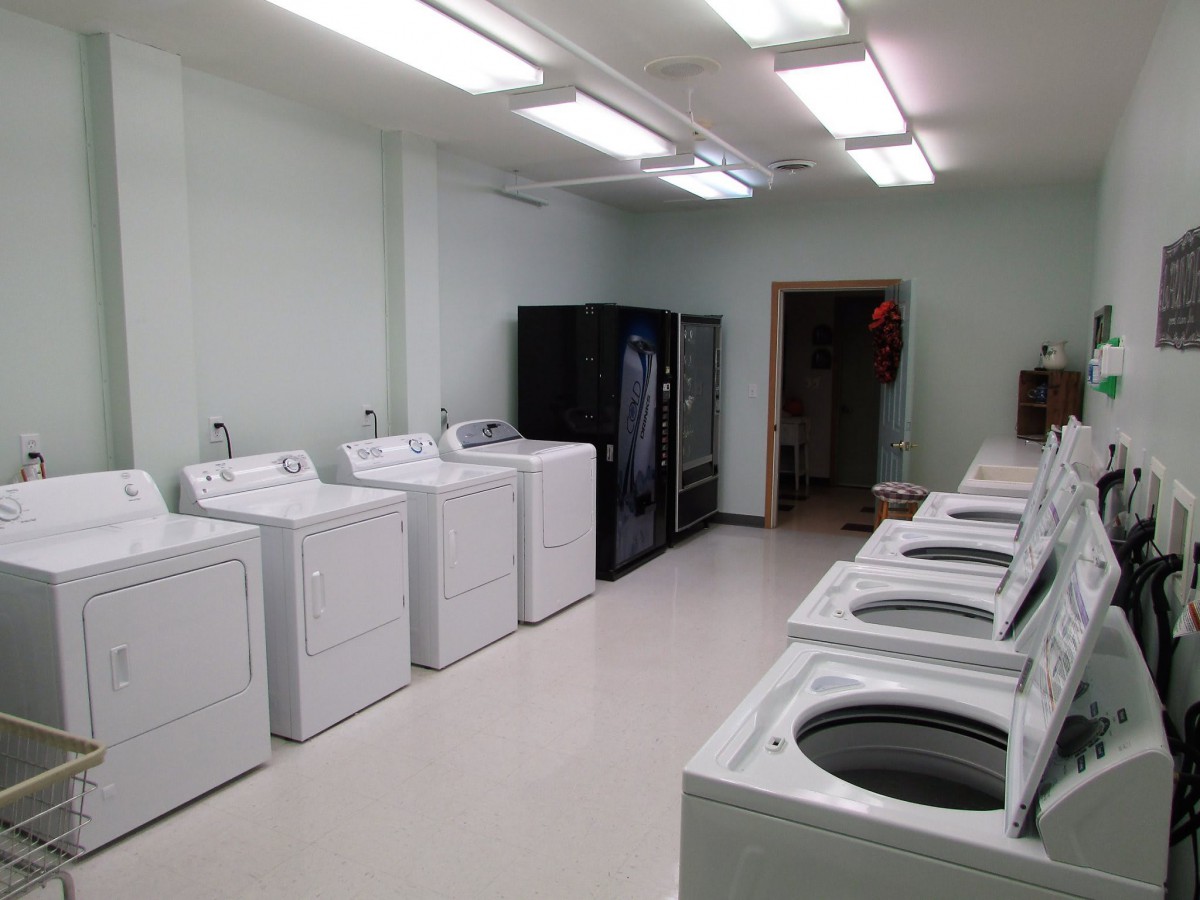A clean and well-organized laundry room with multiple washing machines and dryers.