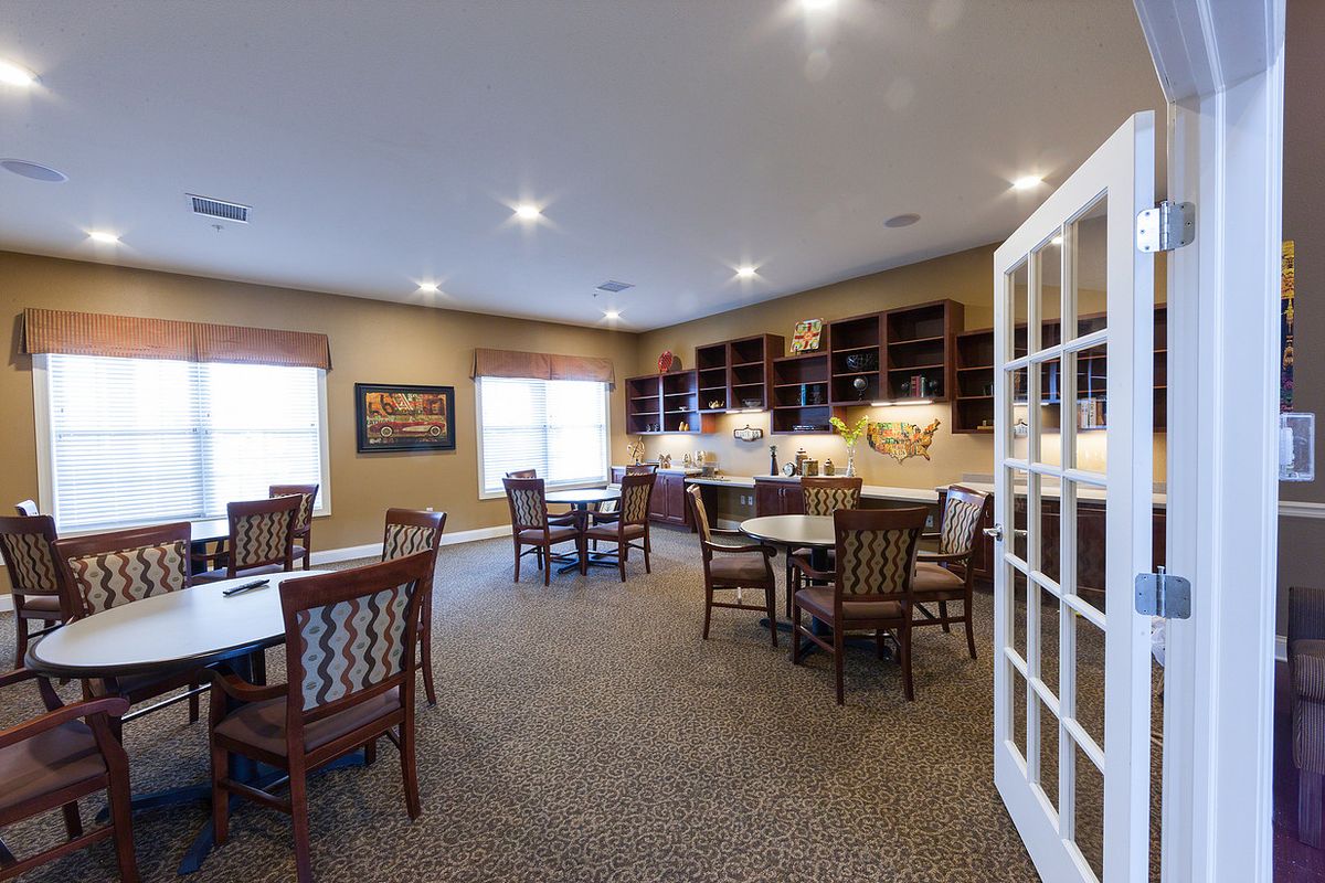 A spacious dining area with multiple tables and chairs, featuring wooden cabinets and cozy lighting.