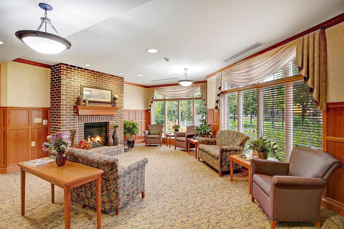 A cozy living room with a fireplace, comfortable seating, and large windows providing natural light.
