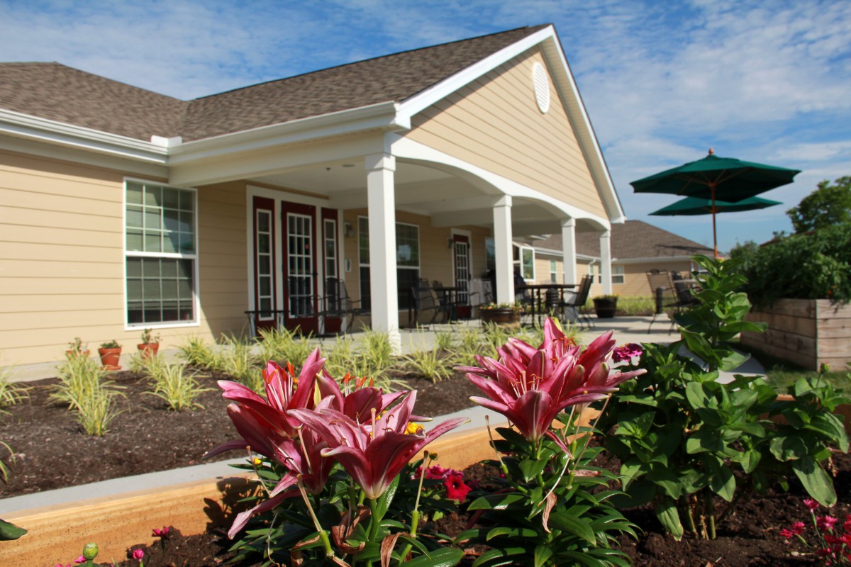 A charming house with a covered porch and landscaped garden featuring blooming flowers.