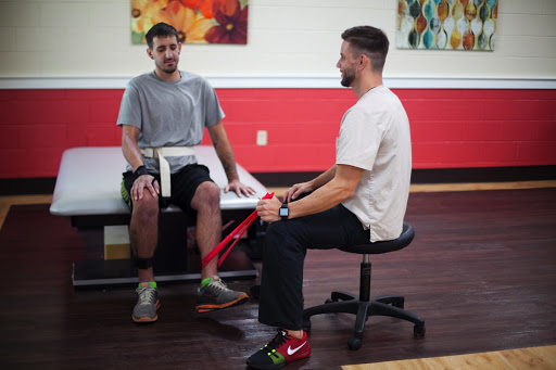 A patient engages in a physical therapy session with a therapist using resistance bands.