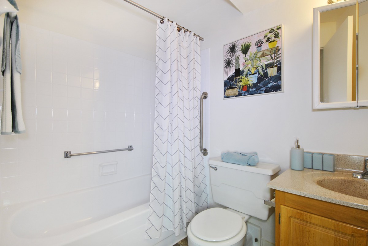 A modern bathroom featuring a bathtub with a shower curtain, a toilet, and a sink.