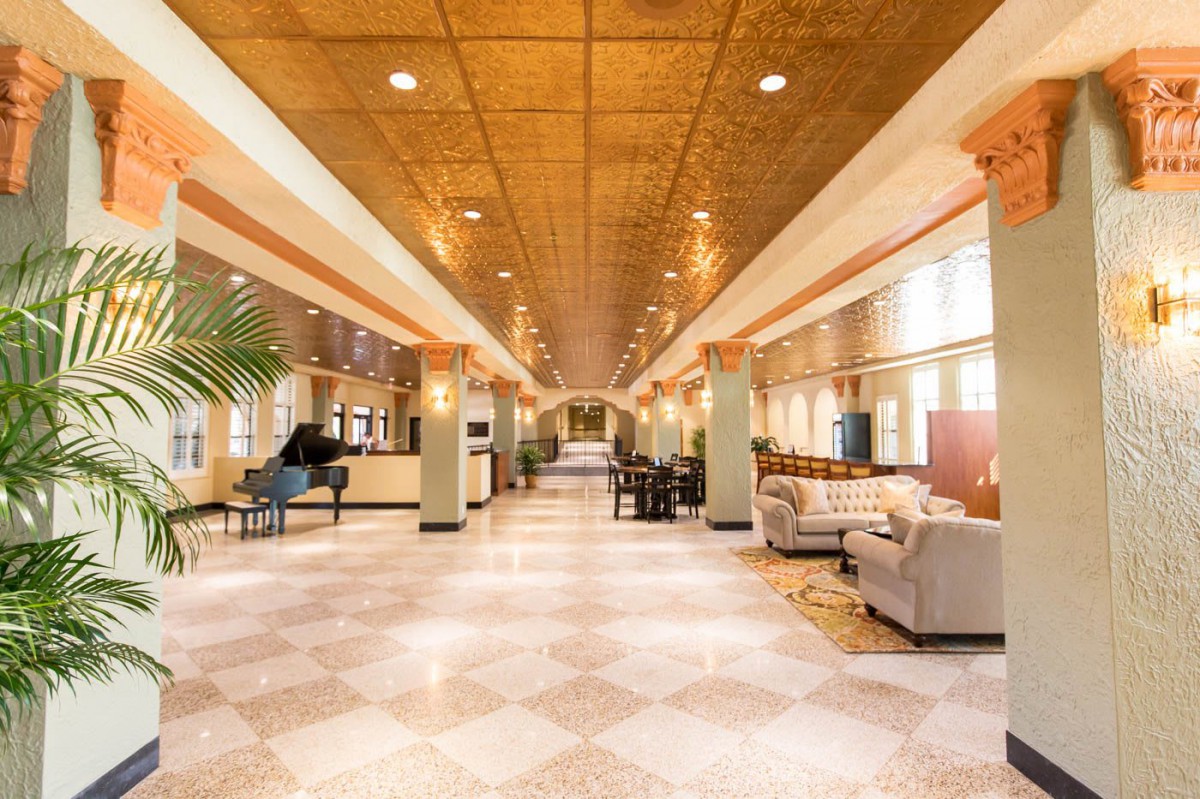 A spacious and elegant lobby featuring comfortable seating, a grand piano, and bright lighting.