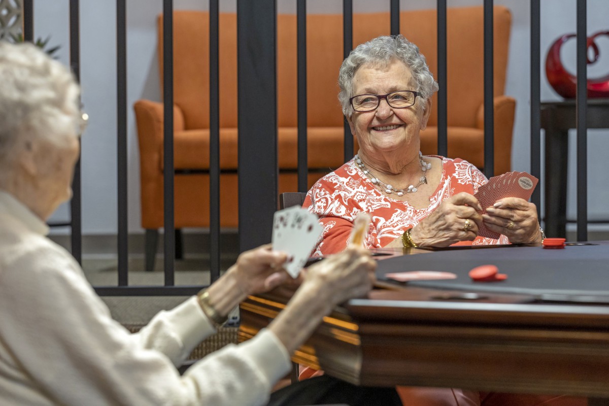 Two elderly women enjoying a card game together indoors.