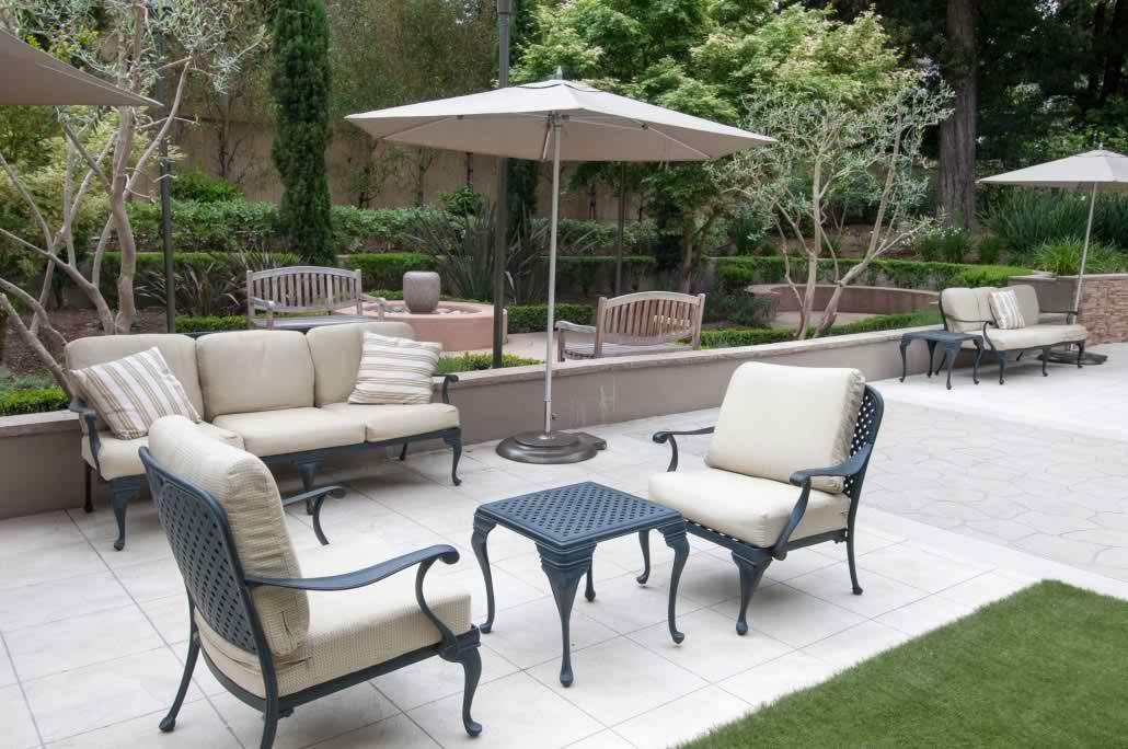 A well-arranged patio with outdoor furniture and an umbrella in a garden setting.