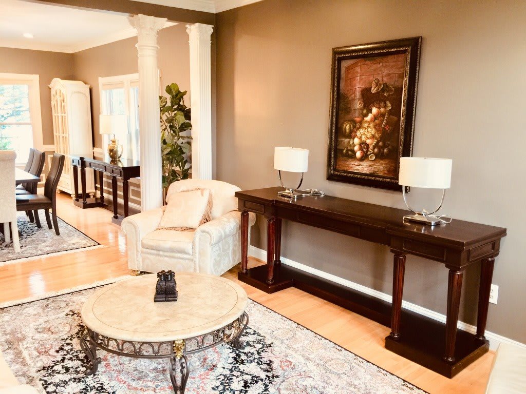 A modern living room with elegant furnishings, featuring a console table, artwork, and comfortable seating.