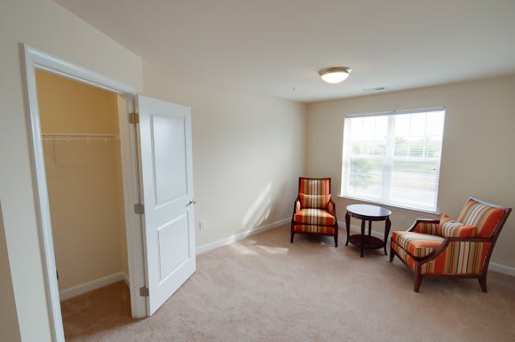 A cozy room with two plaid chairs, a small table, and large window allowing natural light to fill the space.