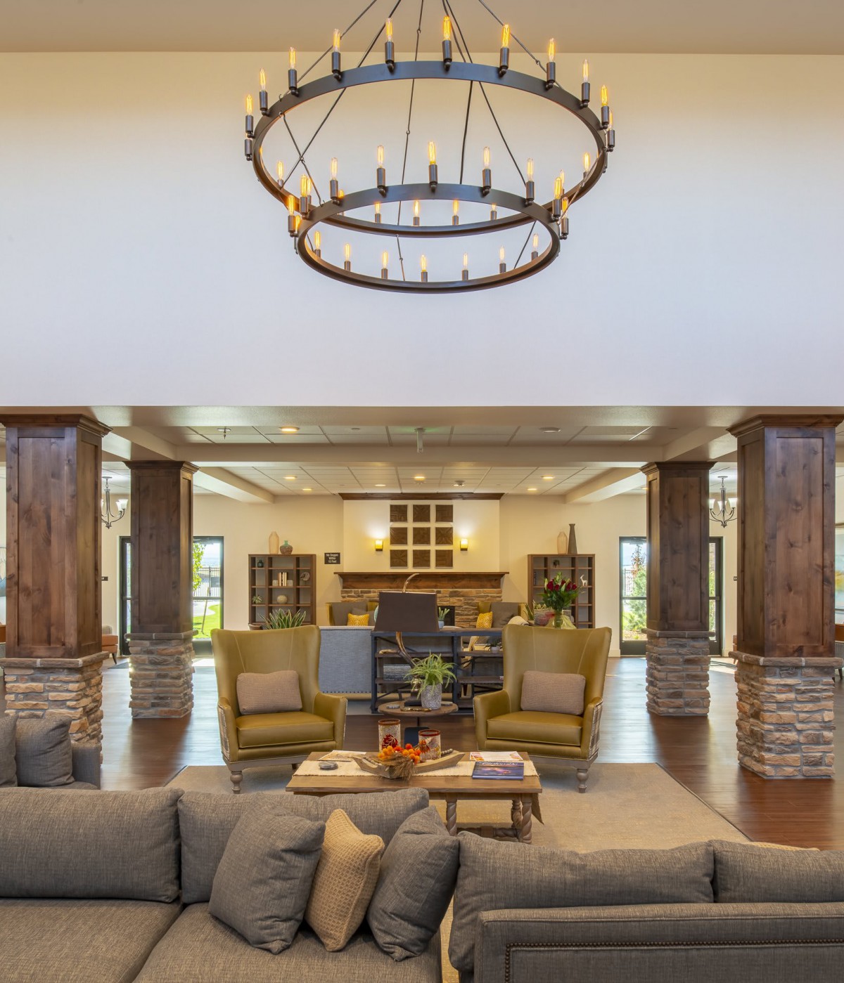 A modern living room with a large chandelier, comfortable seating, and a central fireplace.