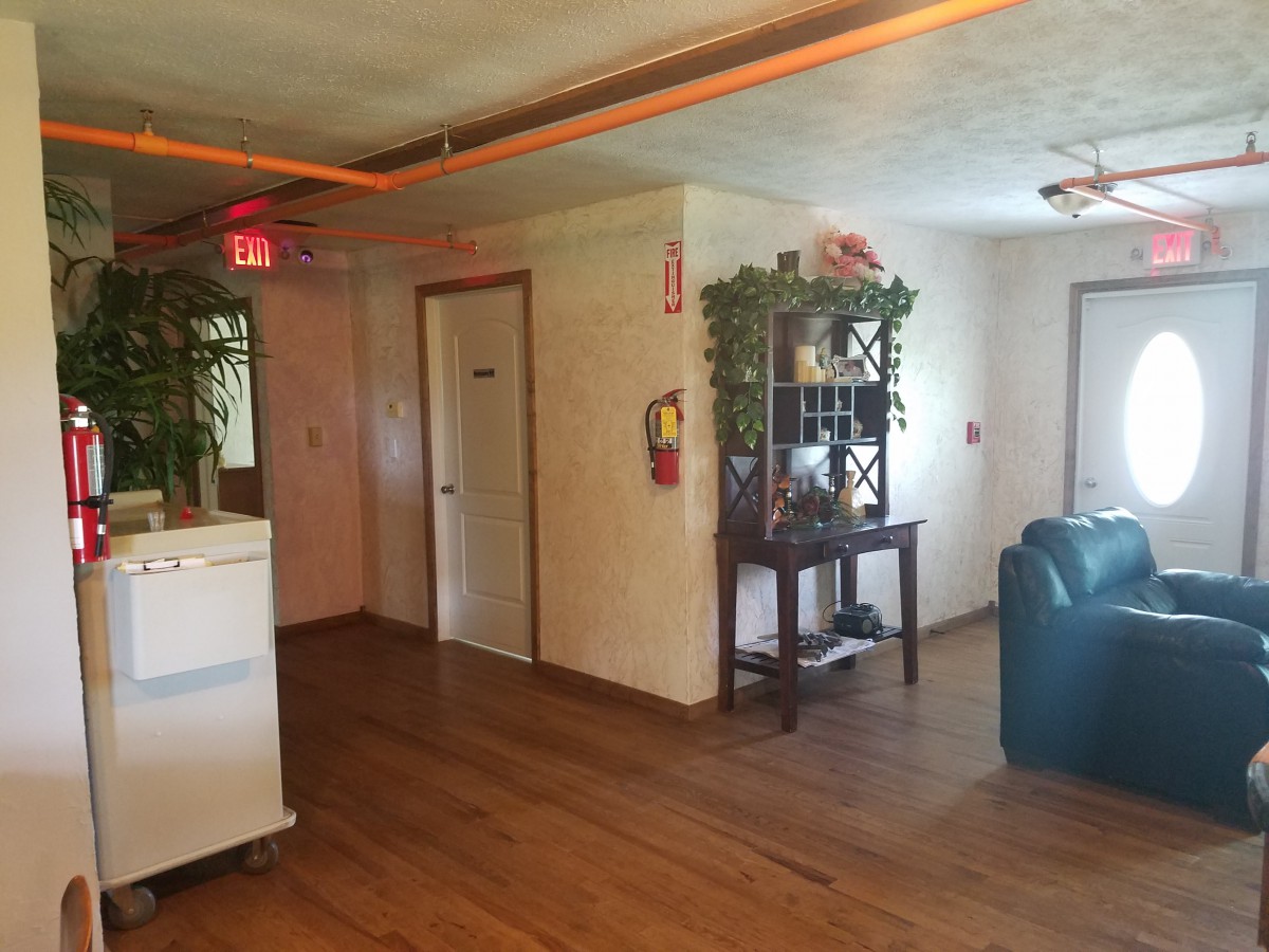 A cozy hallway with wooden flooring, decorated with plants and furniture.
