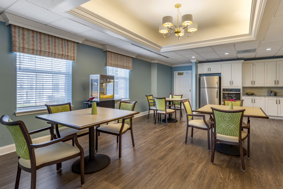 A modern dining area with tables, chairs, and a kitchenette.