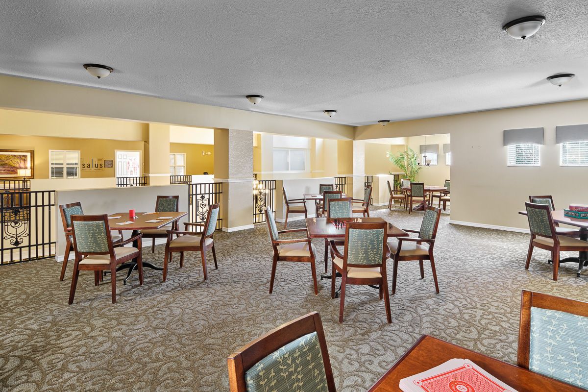 A well-lit dining area with multiple tables and chairs arranged on a carpeted floor.