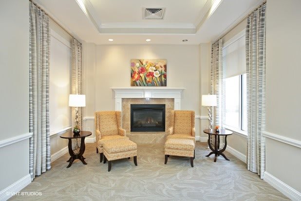 A cozy living room with a fireplace, elegant armchairs, and ambient lighting.