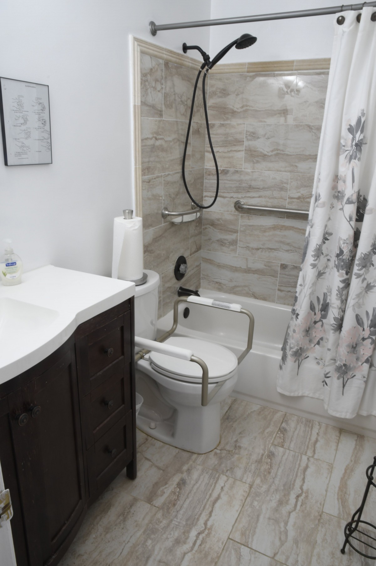 A modern bathroom featuring an accessible design with grab bars and a shower equipped for safety.